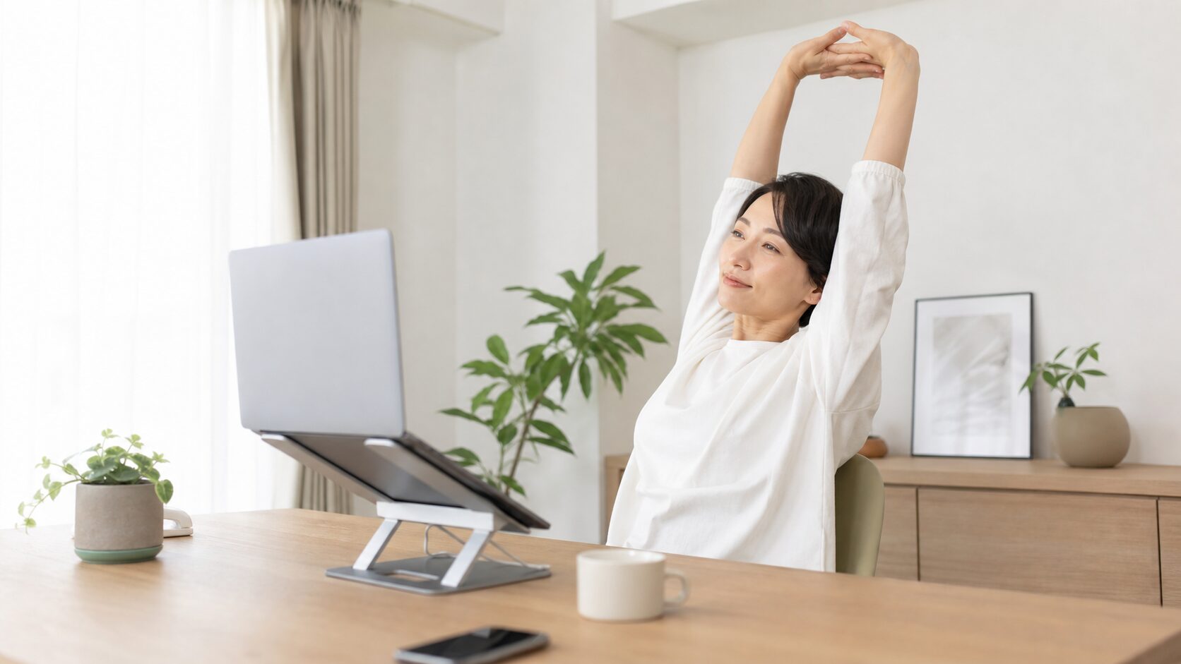 デスクで作業の合間に伸びをして休憩する様子